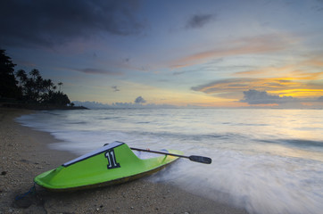 Green canoe at senggigi beach sunset, lombok island, indonesia