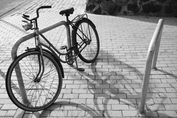 Fototapeta na wymiar S/W Foto altes Fahrrad an einem Fahrradständer mit Schattenwurf der Sonne.Where: Blankenese Strandweg.When: 11.05.2011.