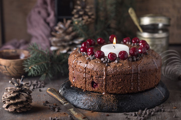 Double chocolate cherry cake with spices and big candle on the rustic background for winter holidays. Christmas and New Year decoration