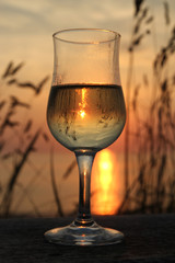 Weinglas mit Weisswein gegen die untergehende Sonne fotografiert.Where: Nordsee-Strand bei...
