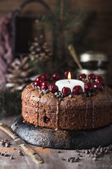 Double chocolate cherry cake with spices and big candle on the rustic background for winter holidays. Christmas and New Year decoration