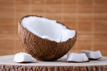 a half of coconut and pieces on natural brown background