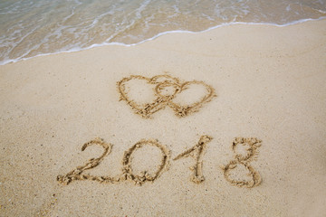 New Year 2018 is coming concept and two hearts drawn on the sand of a beach.