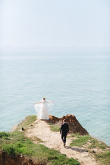 Wedding couple walks towards the cliff