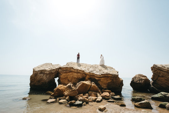 Wedding couple stands on the rocks before the sea