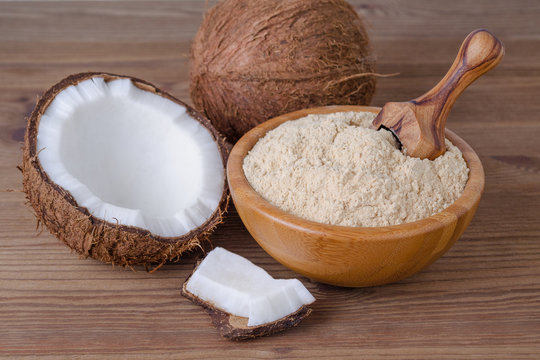 coconut flour in a bowl with scoop on brown wooden background