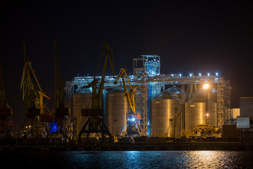 Port grain elevator in night time. Industrial sea trading port bulk cargo zone grain terminal at night
