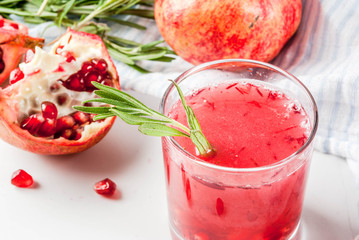 Homemade boozy alcoholic pomegranate cocktail with rosemary and vodka, white marble background, copy space