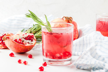 Homemade boozy alcoholic pomegranate cocktail with rosemary and vodka, white marble background, copy space