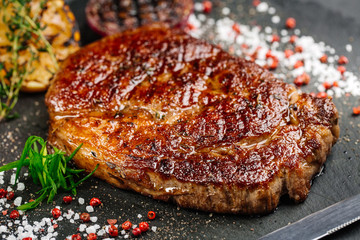 Beef rump steak from marble beef medium rare with grilled lemon and onion on stone plate, close-up. Selective focus.