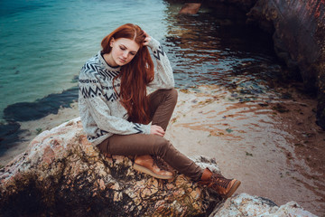 red-haired beautiful young girl on a background of nature, enjoys a beautiful view of the sea.