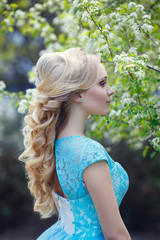 Beautiful blonde young woman wearing fashionable clothes walking in the spring park.