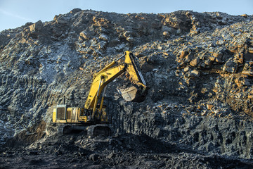 Big yellow dump trucks and excavator in coal mine
