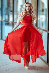 portrait of stylish beautiful girl wearing short red dress posing or walking at the street