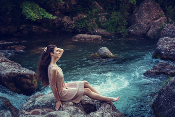 River witch, sitting on a rock in river. Pink dress, a fabulous image.Fashionable toning. Creative color.