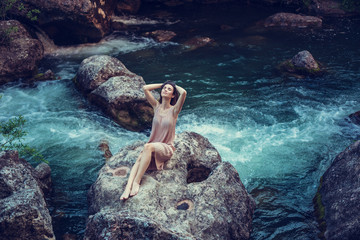 River witch, sitting on a rock in river. Pink dress, a fabulous image.Fashionable toning. Creative color.
