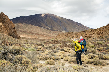 Happy mother with little boy travelling in backpack