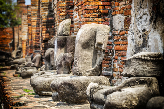 Headless Buddha statues along a temple wall at Wat Mahathat, Temple of the Great Relic, in Ayutthaya, Thailand