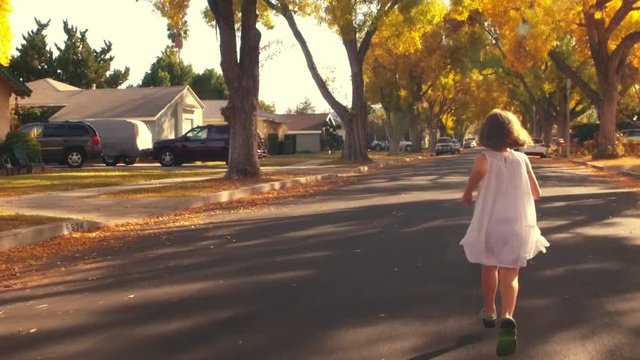 Happy girl child white dress running away POV autumn city street Slow motion