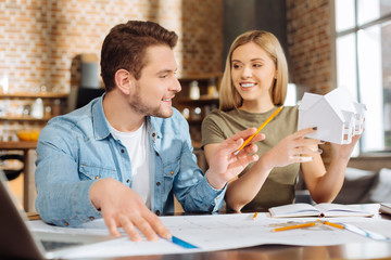 Town plan. Two positive attractive male and female colleagues  drawing city plan while sitting and looking attentively 