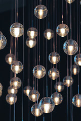  lighting balls on the chandelier in the lamplight,  light bulbs hanging from the ceiling, lamps on the dark background, selective focus, vertical