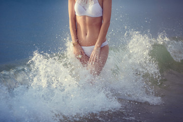 Fototapeta premium adorable sexy girl in bikini enjoying summer. outdoor portrait. Sea waves and white foam. Sunset after the rain on the island