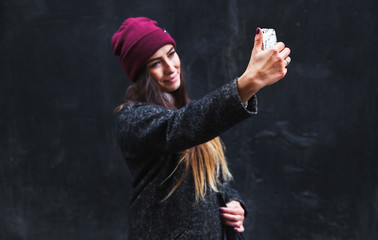 Happy beautiful woman now makes selfie on mobile phone on a black background
