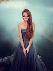 Summer outdoors portrait of beautiful furious scandinavian warrior ginger woman in grey dress with metal chain mail.