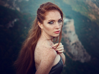 Summer outdoors portrait of beautiful furious scandinavian warrior ginger woman in grey dress with metal chain mail.