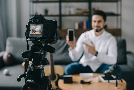 technology blogger pointing on new smartphone with camera on foreground
