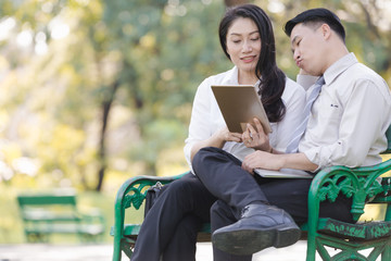 Asian two business men and woman work relaxation in park with laptop