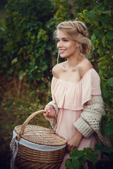 Naklejka na ściany i meble Beautiful blond girl with basket of grapes in a vineyard
