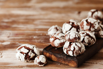 Chocolate crinkle cookies with powdered sugar icing. Cracked chocolate biscuits on baking tray