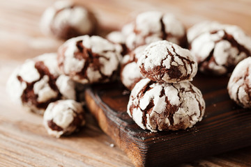 Chocolate crinkle cookies with powdered sugar icing. Cracked chocolate biscuits on baking tray