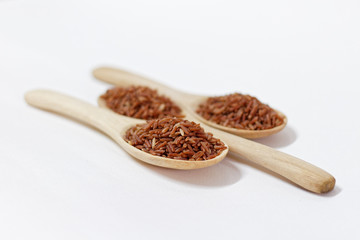 Thai Black or dark brown raw rice in a wooden spoon for a healthy diet. High fiber, vitamin, carbohydrate, minerals, and nutrition for healthy people. on the white background, isolate.