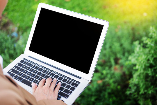 business woman hand using laptop on table in garden.