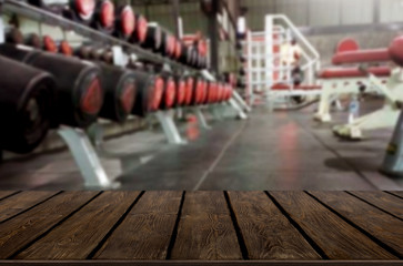 Naklejka na ściany i meble Wooden table on blurred background of fitness gym interior of modern club with equipment for your photomontage or product display.