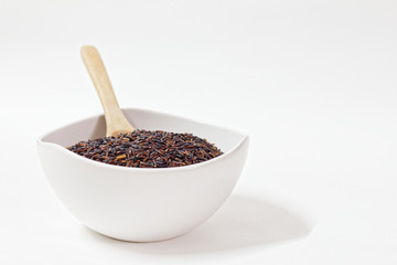 Thai Black or dark brown raw rice in a white bowl for a healthy diet. High fiber, vitamin, carbohydrate, minerals, and nutrition for healthy people. on the white background, isolate.