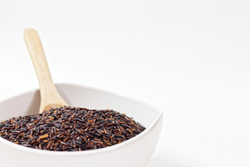 Thai Black or dark brown raw rice in a white bowl for a healthy diet. High fiber, vitamin, carbohydrate, minerals, and nutrition for healthy people. on the white background, isolate.