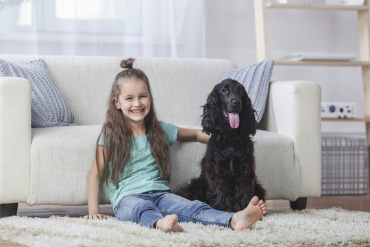 Portrait of cute girl sitting by Cocker Spaniel on rug at home
