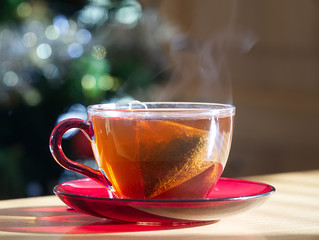 A cup of black tea with a blurred Christmas tree at the background                            