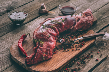close-up shot of raw pork meat with spices on wooden cutting board