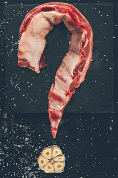 top view of pork meat and garlic in shape of question mark