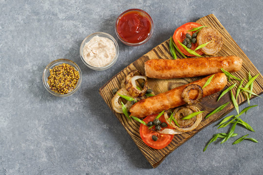 Fried sausages and vegetables on wooden plate