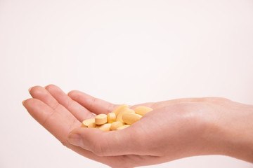 The girl's hand holds a lot of white pills. Health and medicine. White background.