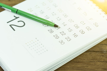 Pen with calendar page closeup on wooden table