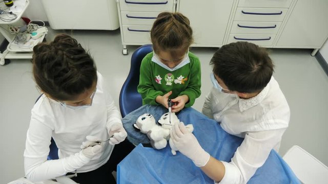 Children treat a toy with dentist using a diferent dental tools. Two little girl play the roles of dentist during a dental check-up