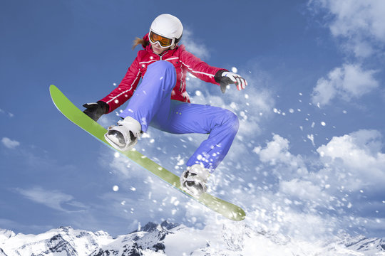 Snowboarderin springt auf ihrem Snowboard durch die Luft
