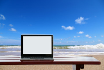 blank screen laptop on the desk on beach Sea holiday background