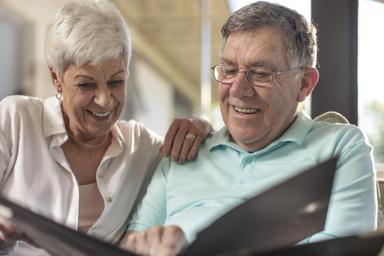 Happy senior couple sitting on couch looking at photo album